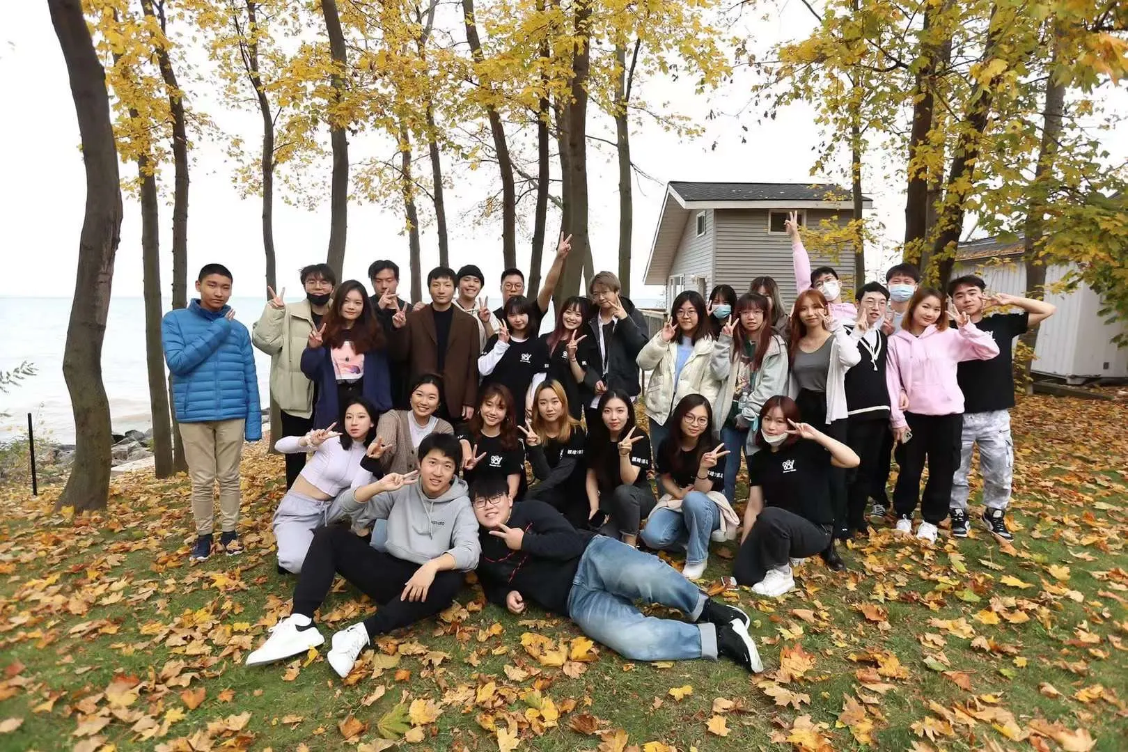 A large group photo under yellow autumn trees