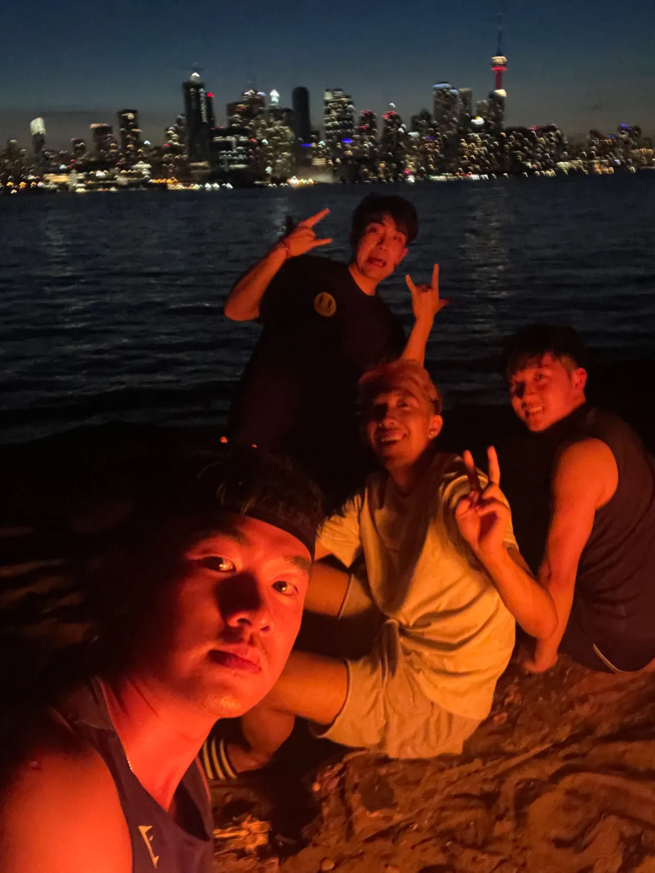 Friends at a beach at night, lit by firelight