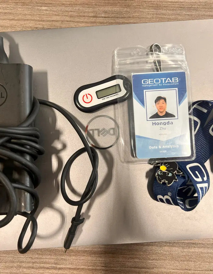 A laptop, a badge and a lanyard laid out on a desk