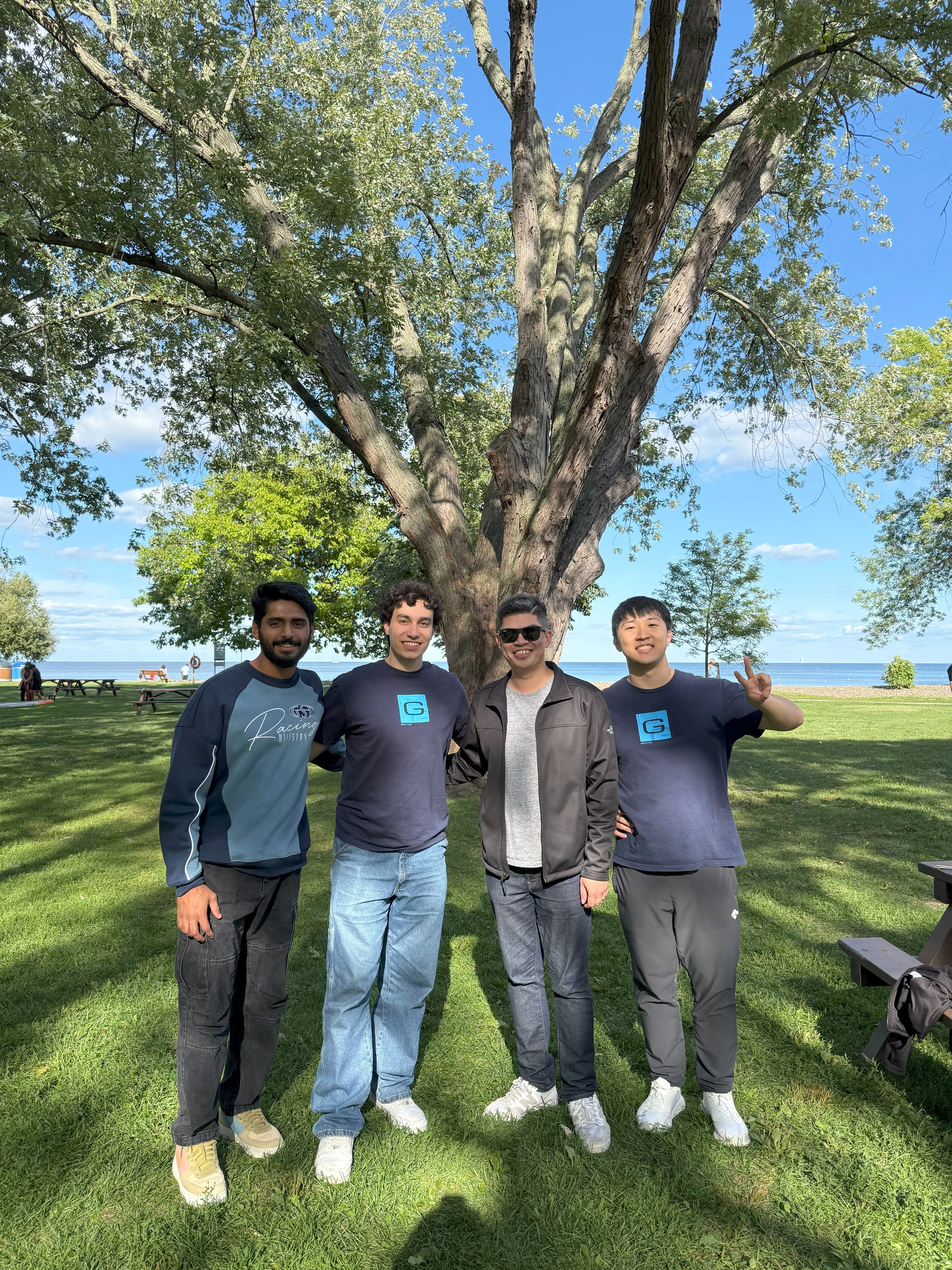 Four friends under a large tree by the lake