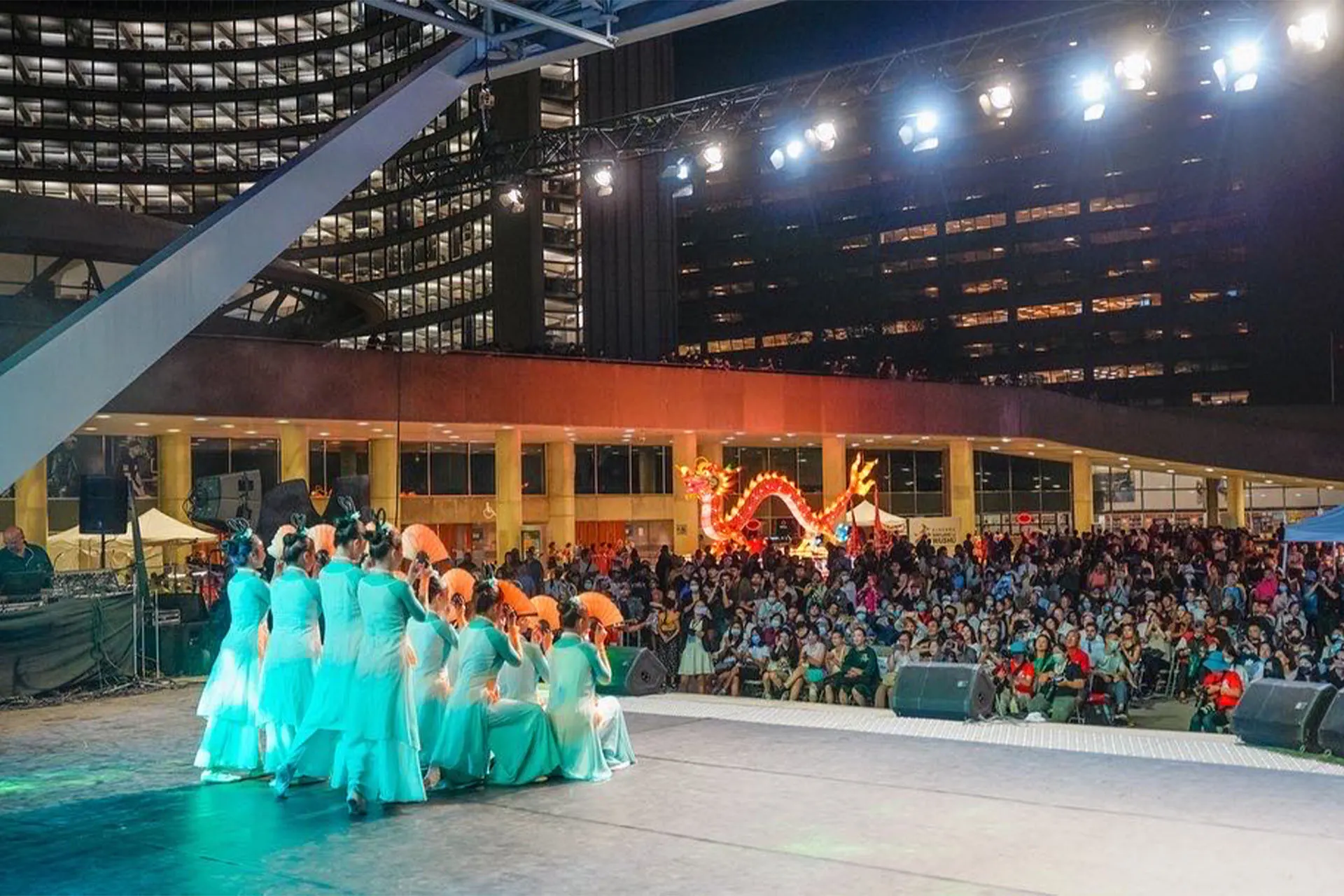 Dancers on the festival stage in front of a large crowd at night