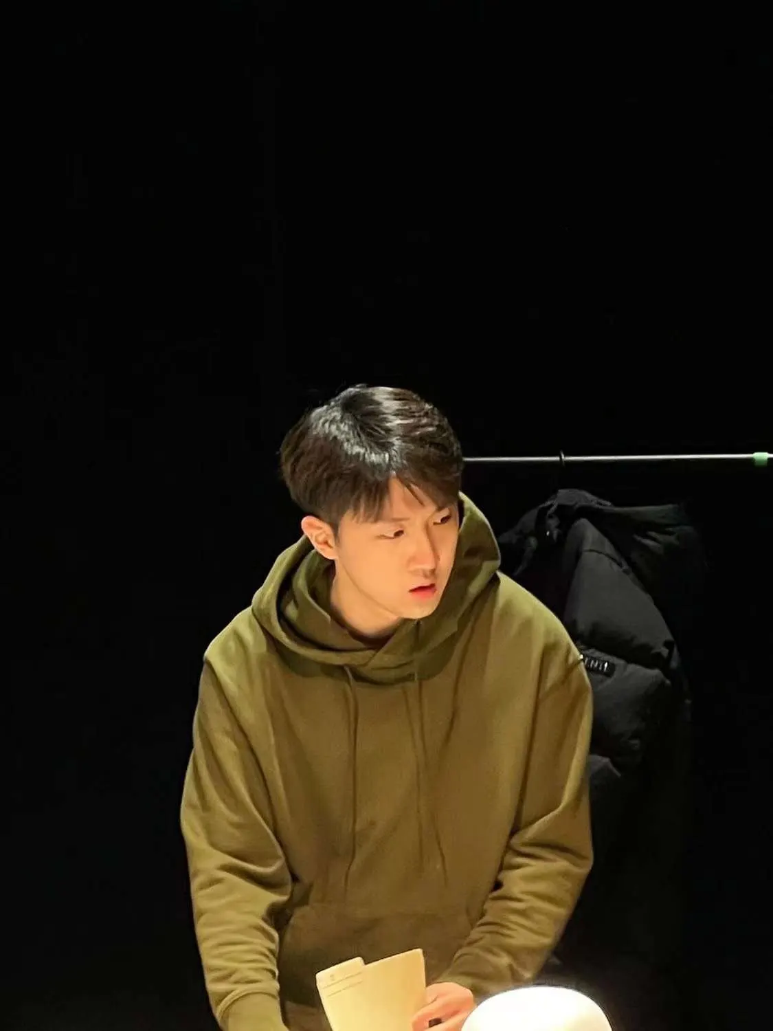 Hongda in an olive hoodie on a dark stage
